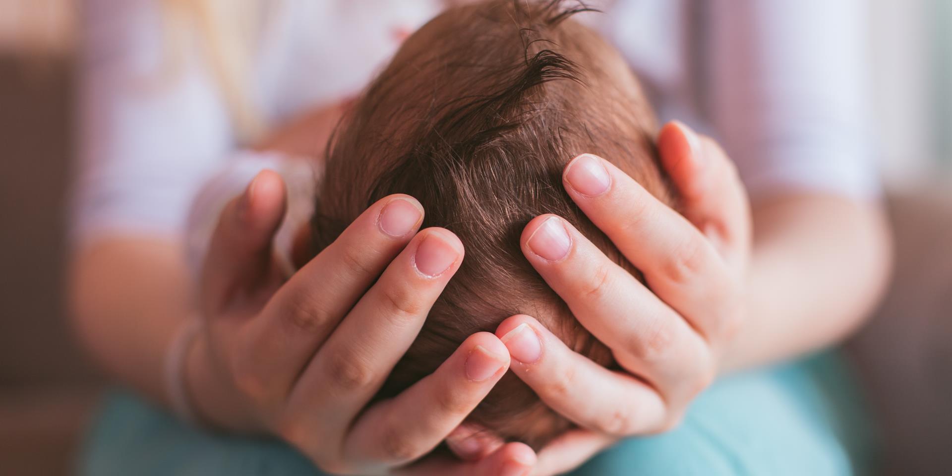 אמא מחזיקה ראש של תינוק בידיים